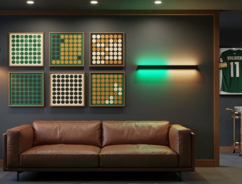Modern game room with framed abstract odds-board style art, emerald and amber LED panel, leather sofa, and blurred bar cart and sports memorabilia, photographed straight-on under warm accent lighting.